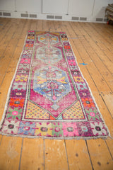 Fringed end of the distressed Oushak runner, showing colorful seed spandrel and floral border.