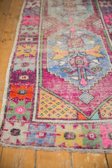 Distressed Oushak runner end, showcasing fringe and vibrant oversized floral border motifs.