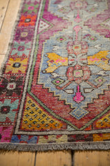 Distressed Oushak rug border showing brick red, saffron yellow, blue, pink geometric patterns.