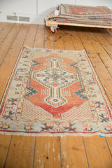 Distressed vintage Oushak rug corner with brick red field, intricate lattice spandrel, and visible wear.