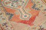 Distressed Oushak rug corner showcasing storied texture, brick red field, and intricate ivory lattice patterns.