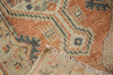 Close-up of distressed Turkish Oushak rug with geometric patterns, revealing fringe and foundation.