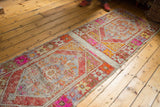 Distressed Oushak runner's central plain-woven band and vivid rust orange, pink diamond medallions.