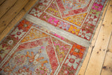 Distressed Oushak runner detail: vibrant rust, pink patterns, worn pile, and plain-woven band.