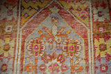 Distressed Oushak runner detail showing diamond motif, rust, pink, and saffron yellow tones.