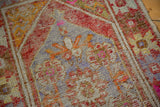 Distressed Oushak runner detail: rust orange, slate blue, and pink tones, with faint foundation.