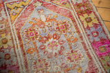 Distressed vintage Oushak runner pile with visible knot heads, rust, slate blue, and pink oversized seed motifs.