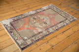 Distressed pale apricot mauve field with intricate vinery corner on a vintage Oushak rug.