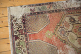 Distressed Oushak rug corner shows wear, pale apricot field, and intricate lattice vinery.