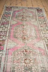 Faded pink, gray, and mint geometric patterns with mostly even wear on this distressed Oushak runner.