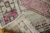 Distressed Oushak rug texture: blush, mint, charcoal tones, pile wear, and intact selvage.