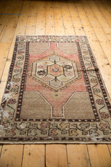 Distressed bottom edge of a vintage Oushak rug, showing short fringe and faded vinery border motifs.