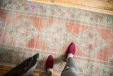Vintage Distressed Oushak runner with muted apricot, ivory, and mint green floral pattern, showing wear.