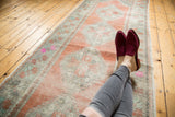 Distressed Oushak runner section showcasing worn patina, faded apricot, and mint motifs.