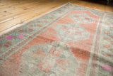 Distressed Oushak runner texture with worn apricot pile and vibrant pink floral border.