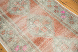 Distressed vintage Oushak runner texture, showing apricot, mint, and bright pink floral motifs.