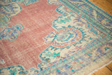 Decorative distressed texture with faded brick red field and blue Oushak medallion pattern.