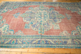 Faded brick red field and royal blue meandering vine border on a distressed Oushak rug.