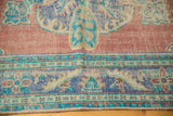 Worn pile texture on a distressed Oushak rug, showing brick red, royal blue, and mint green details.