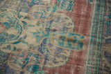 Distressed Oushak rug's worn pile texture with faded brick red, blue, and ivory motifs.