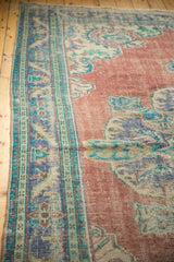 Worn brick red field and royal blue meandering vine border of a vintage Oushak carpet.
