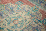 Detailed view of distressed Oushak rug pile, revealing brick red, royal blue, mint, and ivory motifs.