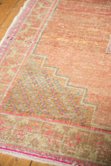 Distressed blush Oushak rug corner showing geometric patterns and vibrant hot pink edge.