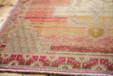 Distressed Oushak rug detail: abrashed blush, sand, and pink geometric border and pile.