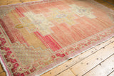 Worn geometric border on distressed Oushak rug, highlighting blush, sand, and red abrash.