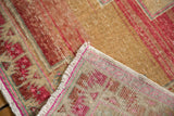 Distressed vintage Oushak rug's folded corner, highlighting abrashed pile and hot pink selvage.