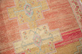 Distressed vintage Oushak rug with heavily abrashed field and primitive blush, sand patterns.