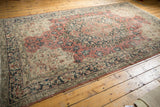 Distressed Oushak rug corner, blush rose and charcoal arabesque border with visible wear.
