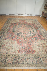 Lower right of vintage distressed Oushak carpet, showing faded blush rose, charcoal, ivory patterns.