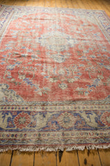Distressed Oushak border detail, faded cherry red and royal blue patterns, worn pile, and fringe.
