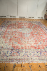 Distressed vintage Oushak carpet with faded cherry red field, blue vinery, and visible wear.