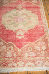 Distressed vintage Oushak rug featuring worn bubblegum pink pile and soft floral border.