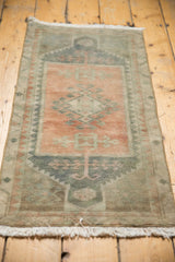 Geometric vinery and low pile texture on distressed Oushak rug in terra cotta and muted teal.