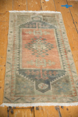 Distressed vintage Oushak rug corner with terra cotta, teal geometric patterns and white fringe.