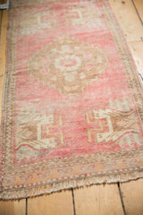 Distressed blush and pale copper Oushak runner texture with geometric patterns and fringe.