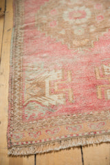 Vintage distressed Oushak rug corner with low pile, blush, ivory, dusty copper tones, and fringe.