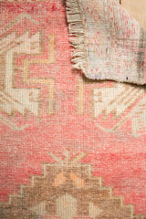 Vintage distressed Oushak rug texture: low pile, blush and ivory geometric pattern, fringe, and knotted back.