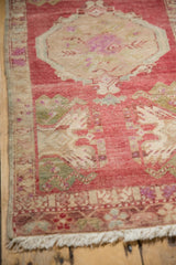 Distressed Oushak runner corner, raspberry red field with green plant motifs and fringe.
