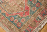 Distressed Oushak rug corner with low pile, dusty red, teal, and sand floral border.