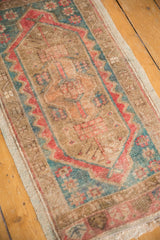 Distressed Oushak rug corner, showcasing teal and blush floral cross sections with low pile.