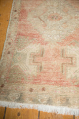 Vintage distressed Oushak rug featuring muted dusty rose, silver patterns, low pile, and white fringe.