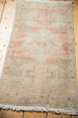 Distressed Oushak rug corner with soft dusty rose and antique ivory tones, showing fringe.
