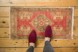 Vintage distressed Oushak rug mat with stepped raspberry medallion and bronze-silver field, blush plant motifs.