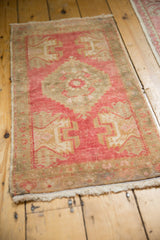 Distressed Oushak rug corner with raspberry red geometric motifs and intact side selvage.