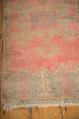 Distressed Oushak rug's decorative lower border with rose and silver plant motifs and fringe.