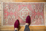Close-up of distressed blush pink Oushak rug with stepped medallion and worn texture.